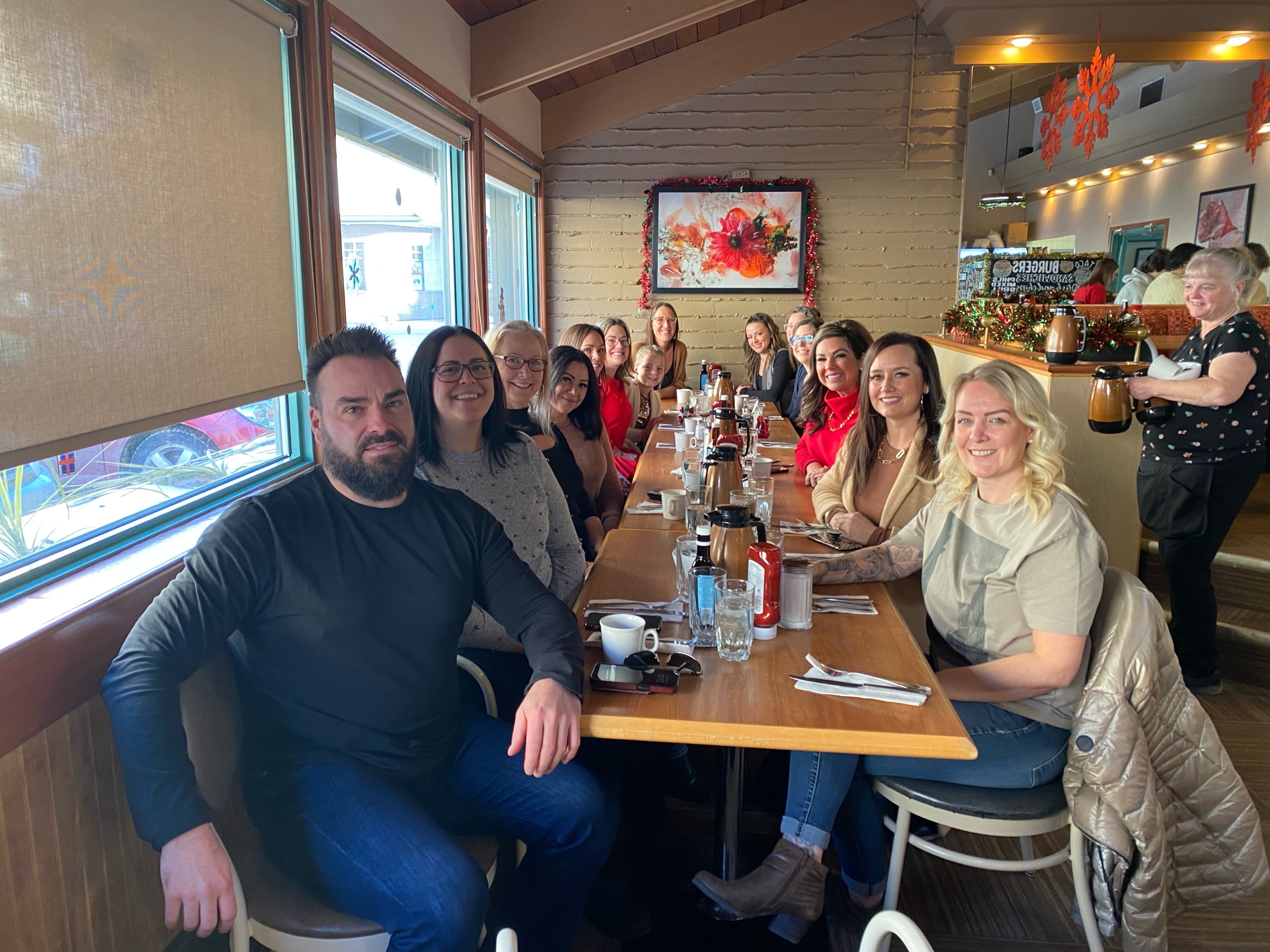 alt="TPTM team members seated at a table in a restaurant"