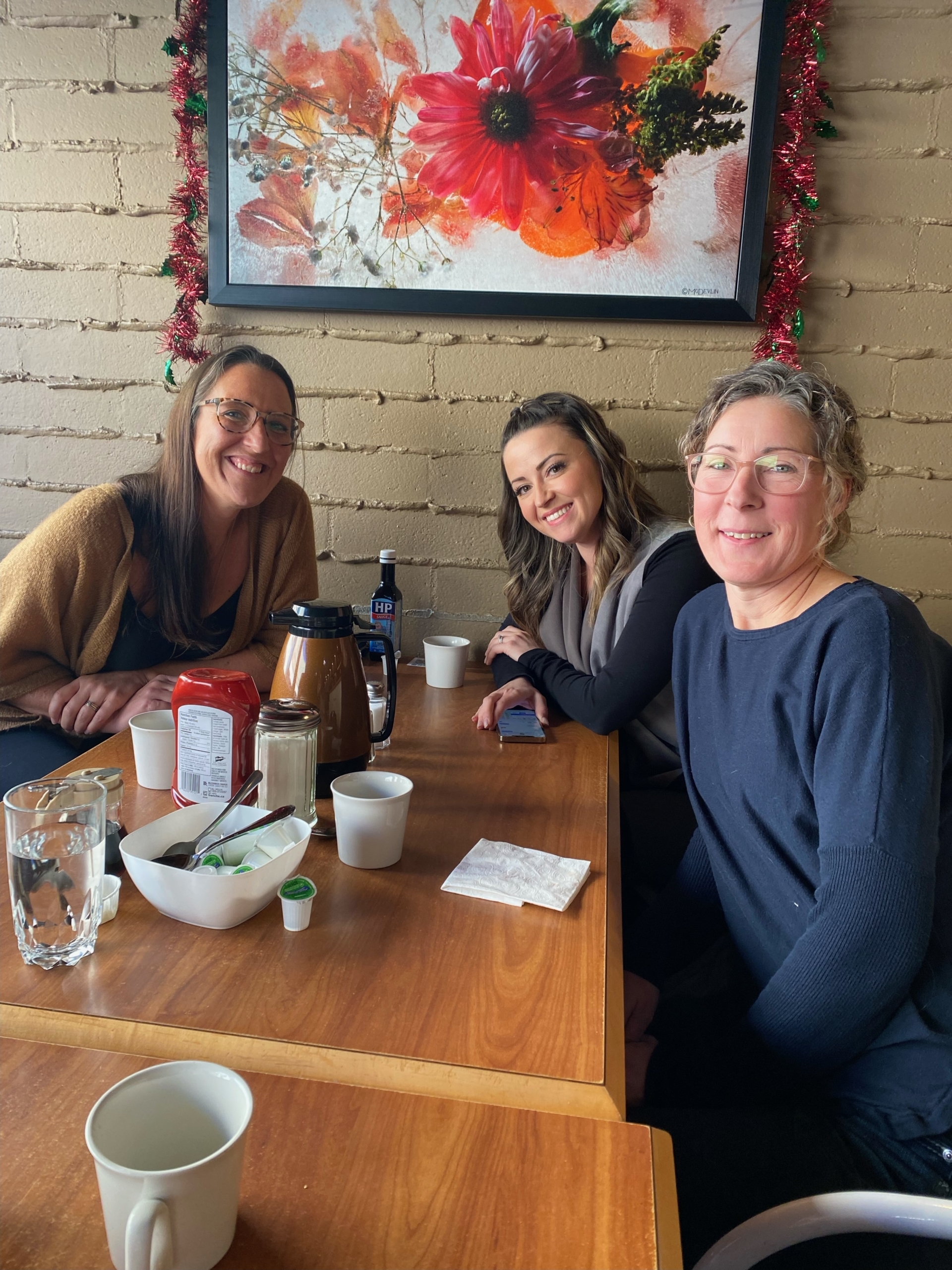 alt="Three TPTM team members at a table in the restaurant"